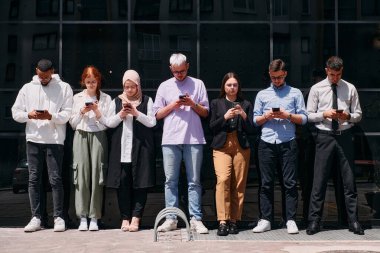 Çeşitli ve kendine güvenen bir grup iş adamı birlikte poz veriyor, başarı, hırs ve birlik yayıyor, dinamik ve ilham verici bir iş ortamının özünü yakalıyorlar..