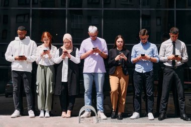 Çeşitli ve kendine güvenen bir grup iş adamı birlikte poz veriyor, başarı, hırs ve birlik yayıyor, dinamik ve ilham verici bir iş ortamının özünü yakalıyorlar..