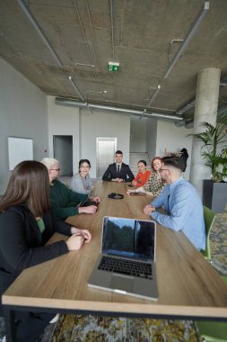 Çeşitli etnik çeşitlilikte bir iş ekibi, modern ofis ortamında strateji ve çözümleri tartışan bir işbirliği toplantısı düzenliyor..