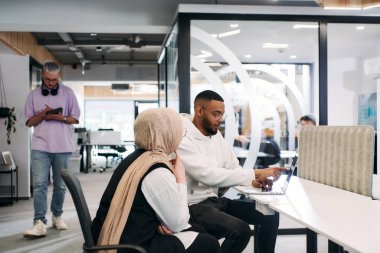 Modern bir ofis ortamında, Afrikalı bir Amerikalı işadamı ve onun Müslüman meslektaşı, tesettür takıyor, işbirlikçi tartışmalara girişiyor, çeşitli iş görevlerini ele alıyor ve sorunları çözüyorlar.