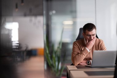 Modern bir ofiste evrakları inceleyen odaklı muhasebeci, bir dizüstü bilgisayar üzerinde çalışan iş adamı, dinamik bir açık mekan ortamında günlük kıyafet giyme işinde profesyonel..