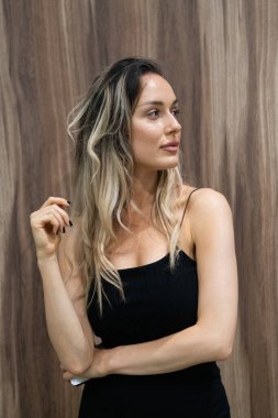 Çekici, siyah elbiseli sarışın bir kadın zarifçe poz verir, kendine güven, zarafet ve cazibe saçar..