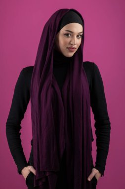 Başörtülü çarpıcı bir Müslüman kadın zarif bir şekilde stüdyoda pembe bir arka plana karşı poz veriyor, zarafet ve güven yayıyor.. 