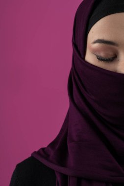 Başörtülü çarpıcı bir Müslüman kadın zarif bir şekilde stüdyoda pembe bir arka plana karşı poz veriyor, zarafet ve güven yayıyor.. 