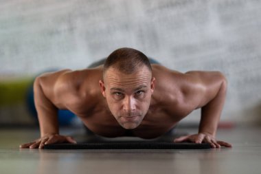 Spor salonunda şınav çeken kaslı bir adam. Güç, dayanıklılık ve kendini spora adamış.