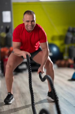 Kararlı bir adam, spor salonundaki savaş halatlarıyla yoğun kardiyo egzersizleri yaparken limitlerini zorlar. Gücünü, dayanıklılığını gösterir ve odaklanır.. 