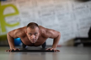 Spor salonunda şınav çeken kaslı bir adam. Güç, dayanıklılık ve kendini spora adamış.