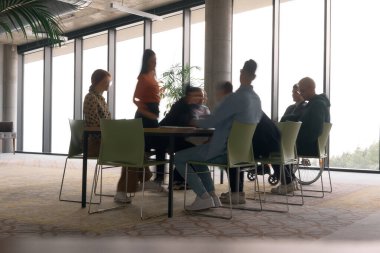 Bir konferans masasının etrafında acil olarak çalışan çeşitli bir iş ekibi, yöneticileri tekerlekli sandalyede oturmuş, görüşlerini beklerken bir toplantıda işbirliği yapıyor.. 