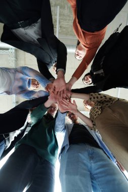 Bir grup profesyonel iş adamı, birlik ve takım çalışmasını sembolize etmek için el ele tutuşuyorlar.