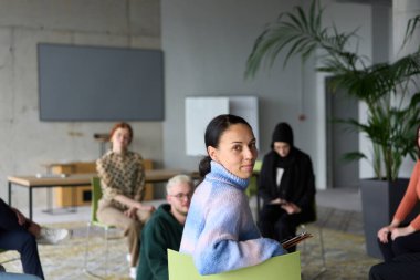 Çeşitli iş adamları modern bir ofiste dikkatle oturup, bir eğitmenin önderliğindeki bir eğitim oturumunda aktif olarak en son teknolojik gelişmelere odaklanırlar.