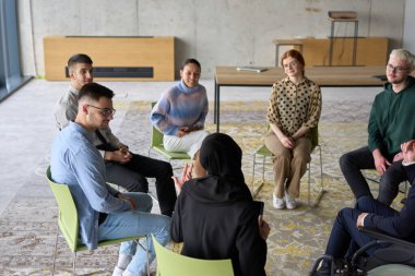 Şirket işletme ekibi bir yönetici veya koçla toplantı yapıyor. Bir grup mutlu, çok ırklı insan bir çemberin içinde oturuyor. .