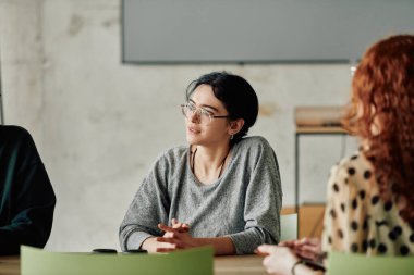Çeşitli etnik çeşitlilikte bir iş ekibi, modern ofis ortamında strateji ve çözümleri tartışan bir işbirliği toplantısı düzenliyor..