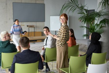 Çeşitli iş adamları modern bir ofiste dikkatle oturup, bir eğitmenin önderliğindeki bir eğitim oturumunda aktif olarak en son teknolojik gelişmelere odaklanırlar.