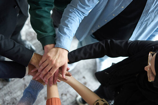 Верхний вид деловых людей, объединяющих руки в круг, символизирующий единство, сотрудничество и общий успех на рабочем месте.