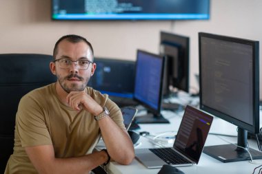 Bir programcı ofisinde otururken akıllı telefon uygulamalarını özenle test eder