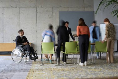 Bir konferans masasının etrafında acil olarak çalışan çeşitli bir iş ekibi, yöneticileri tekerlekli sandalyede oturmuş, görüşlerini beklerken bir toplantıda işbirliği yapıyor.. 