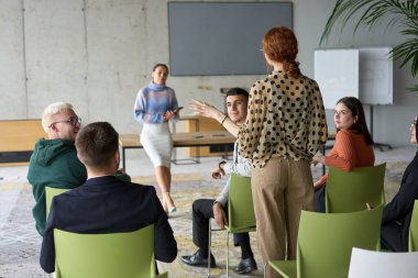 Çeşitli iş adamları modern bir ofiste dikkatle oturup, bir eğitmenin önderliğindeki bir eğitim oturumunda aktif olarak en son teknolojik gelişmelere odaklanırlar.