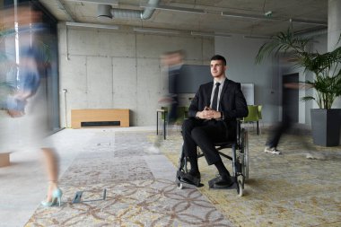 İşbirliği ve iş birliğiyle aktif olarak meşgul olan iş arkadaşları tarafından çevrelenmiş, meşgul bir ofiste gezinen tekerlekli sandalyedeki bir işadamı. 