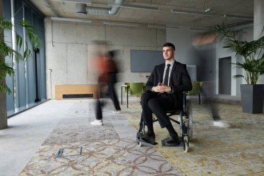 İşbirliği ve iş birliğiyle aktif olarak meşgul olan iş arkadaşları tarafından çevrelenmiş, meşgul bir ofiste gezinen tekerlekli sandalyedeki bir işadamı. 