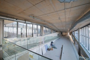 Yapım aşamasındaki modern bir iş binasının büyüleyici bir görüntüsü, çiğ endüstriyel iç mekânını, gün batımının sıcak, altın sarısı renkleri ile yıkanmış çelik kirişleri ve beton duvarlarıyla sergiliyor.. 