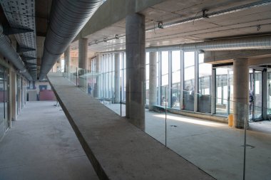 Yapım aşamasındaki modern bir iş binasının büyüleyici bir görüntüsü, çiğ endüstriyel iç mekânını, gün batımının sıcak, altın sarısı renkleri ile yıkanmış çelik kirişleri ve beton duvarlarıyla sergiliyor.. 