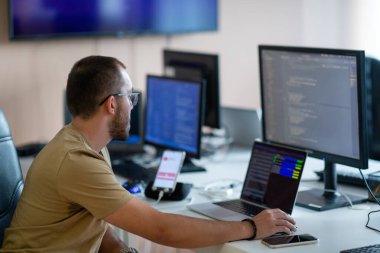 Bir programcı ofisinde otururken akıllı telefon uygulamalarını özenle test eder