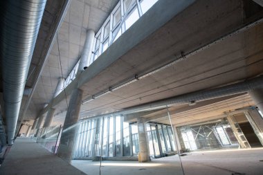 Yapım aşamasındaki modern bir iş binasının büyüleyici bir görüntüsü, çiğ endüstriyel iç mekânını, gün batımının sıcak, altın sarısı renkleri ile yıkanmış çelik kirişleri ve beton duvarlarıyla sergiliyor.. 