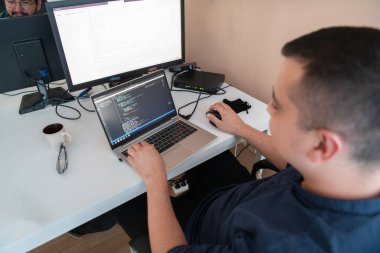 Bir programcı ofisinde otururken akıllı telefon uygulamalarını özenle test ediyor. Yüksek kalite fotoğraf