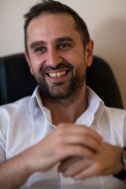 Ofiste otururken akıllı telefonuyla konuşan bir işadamı profesyonel tavrını ve aktif iletişimini gösteriyor.