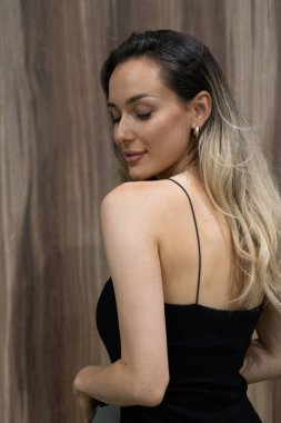 Çekici, siyah elbiseli sarışın bir kadın zarifçe poz verir, kendine güven, zarafet ve cazibe saçar..