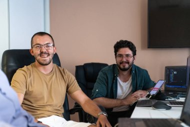 Programcılardan oluşan dinamik bir ekip bilgisayarlarında canlı bir tartışma ve problem çözme, ofiste işbirliği ve yaratıcılığı teşvik ediyor.