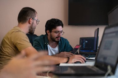 Programcılardan oluşan dinamik bir ekip bilgisayarlarında canlı bir tartışma ve problem çözme, ofiste işbirliği ve yaratıcılığı teşvik ediyor.