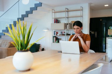 Oturma odasında oturan bir kadın bilgisayarla kameraya bakıyor iş arkadaşlarıyla görüntülü konuşma, vesikalık fotoğraf. İş görüşmesi soruları yanıtlıyor