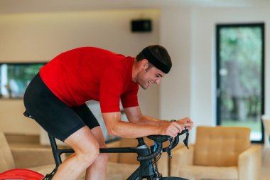 Modern bir oturma odasında triatlon bisikleti süren bir triatloncu.. 