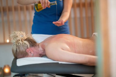 Profesyonel bir masaj terapisti ellerine aromatik yağ dökerek huzurlu bir kaplıca ortamında rahatlatıcı ve canlandırıcı bir masaj seansı hazırlar. 