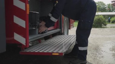 Profesyonel bir itfaiyeci tehlikeli metal kesme ekipmanlarını itfaiye aracında titizlikle hazırlar ve acil durumlarda yüksek riskli kurtarma operasyonlarına hazır olduklarını gösterir..