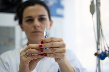 Beyaz önlüklü, odaklanmış bir hemşire profesyonel bir sağlık ortamında enjeksiyon için dikkatlice bir şırınga hazırlar.