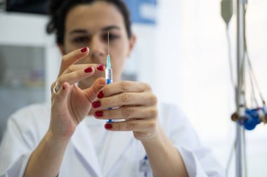 Beyaz önlüklü, odaklanmış bir hemşire profesyonel bir sağlık ortamında enjeksiyon için dikkatlice bir şırınga hazırlar.