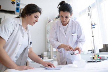 Bir hastane laboratuvarında iki hemşire hastalar ve hastane kullanımı için ilaçları dikkatlice inceliyor ve hazırlıyorlar.