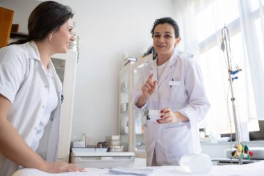 Bir hastane laboratuvarında iki hemşire hastalar ve hastane kullanımı için ilaçları dikkatlice inceliyor ve hazırlıyorlar.