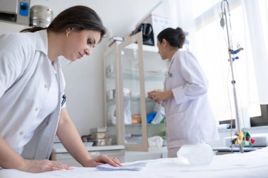 Bir hastane laboratuvarında iki hemşire hastalar ve hastane kullanımı için ilaçları dikkatlice inceliyor ve hazırlıyorlar.