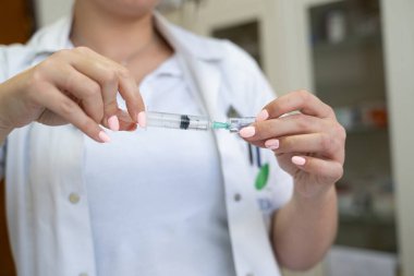 Beyaz önlüklü, odaklanmış bir hemşire profesyonel bir sağlık ortamında enjeksiyon için dikkatlice bir şırınga hazırlar.