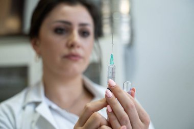 Beyaz önlüklü, odaklanmış bir hemşire profesyonel bir sağlık ortamında enjeksiyon için dikkatlice bir şırınga hazırlar.