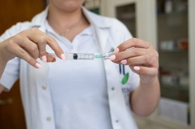 Beyaz önlüklü, odaklanmış bir hemşire profesyonel bir sağlık ortamında enjeksiyon için dikkatlice bir şırınga hazırlar.
