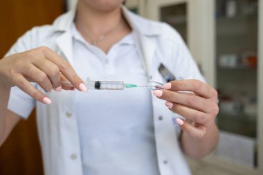 Beyaz önlüklü, odaklanmış bir hemşire profesyonel bir sağlık ortamında enjeksiyon için dikkatlice bir şırınga hazırlar.