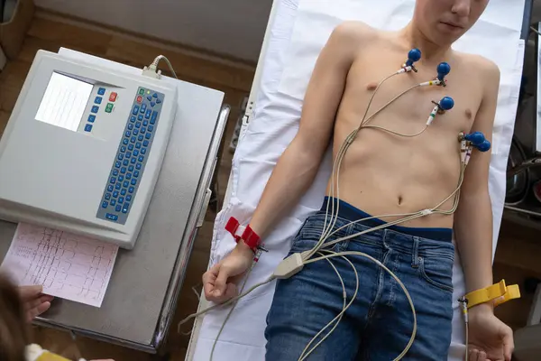 Kadın bir doktor, hastane odasında genç bir adama EKG çeker. Rutin bir kontrol sırasında kalp sağlığını dikkatle izler.