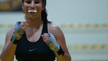 Kickboks yapan kadın boksör yumruklarını çalıştırırken kız hızlı saldırırken spor salonunda günlük antrenman yapıyor. Yüksek kalite 8K görüntü