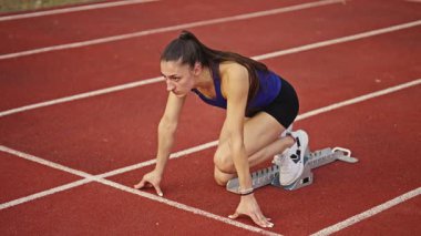 Atletizm atletizm sprint yarışı koşucusu koyu bir arka planda, stadyumun pistinde spor ayakkabılarla koşu koşusuna çıkıyor. Yavaş çekim