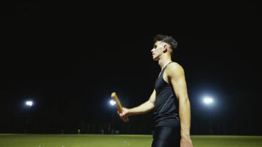 Erkek atlet, atletizm yarış pisti takım çalışması konseptinde bayrak yarışı sopasıyla oynuyor. Yüksek kalite ağır çekim 4k görüntü