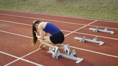 Atletizm atletizm sprint yarışı koşucusu koyu bir arka planda, stadyumun pistinde spor ayakkabılarla koşu koşusuna çıkıyor. Yavaş çekim